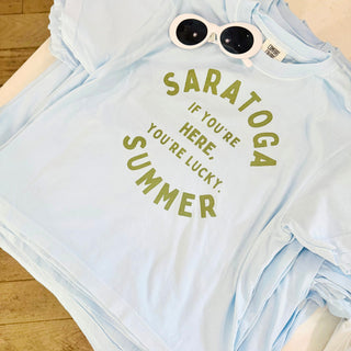 Light blue t-shirt with 'Saratoga Summer - If You're Here, You're Lucky.' text. Saratoga Springs, NY Boutique